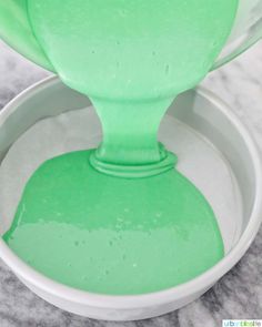 a white bowl filled with green liquid on top of a counter