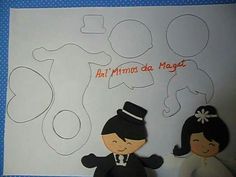 two paper dolls are sitting next to each other in front of a white board with words on it