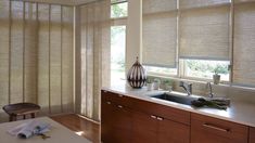 a kitchen area with counter, sink and window coverings on the windowsill is shown