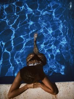 a woman is standing in front of a pool with her head above the water's surface