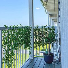 a potted plant sitting on top of a wooden porch next to a white fence