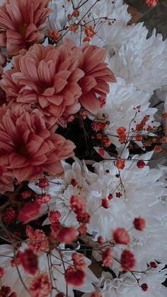 pink and white flowers are in the middle of an arrangement with red accents on it