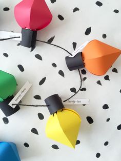 several different colored paper lights on a white surface