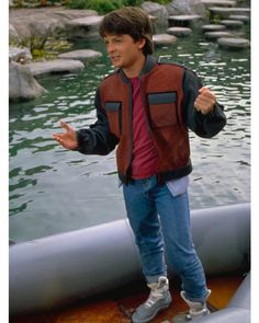 a young man standing on top of a boat in the water with his arms out