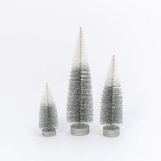 three silver christmas trees sitting on top of each other in front of a white background