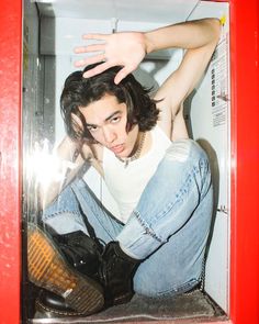 a young man sitting in a microwave with his hand on top of his head