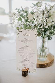 a menu card sitting on top of a table next to a vase filled with flowers