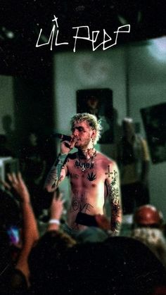 a man with tattoos and piercings on his chest standing in front of a crowd