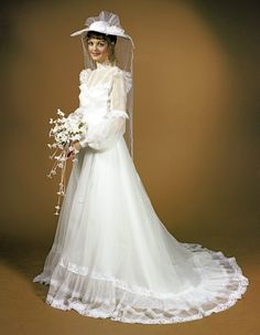 a woman in a white wedding dress and veil holding a flower bouquet with her right hand