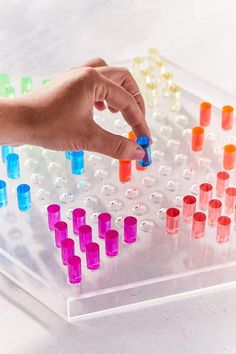 a person's hand is touching an array of colored liquids in a test tube