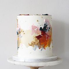 a white cake with multicolored icing and gold sprinkles on top