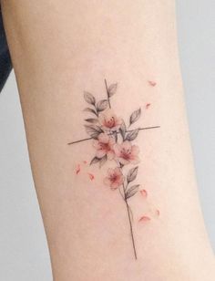 a small cross with flowers on the side of her leg and behind it is a tattoo