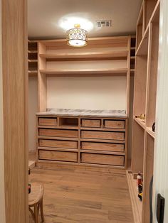 an empty walk in closet with lots of drawers and wooden shelves on the wall next to it