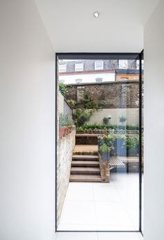 an open door leading to a patio with stairs and potted plants on either side