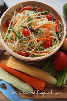 a wooden bowl filled with vegetables on top of a cutting board