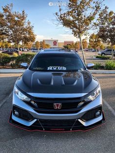 the front end of a silver honda civic hatchback parked in a parking lot with other cars