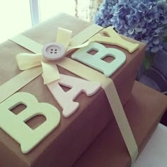 a gift wrapped in brown paper with the word baby spelled out on it and a bow