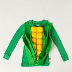 a child's green long sleeved shirt with a yellow pea inside