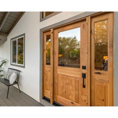 two wooden doors on the side of a house next to a chair and potted plant