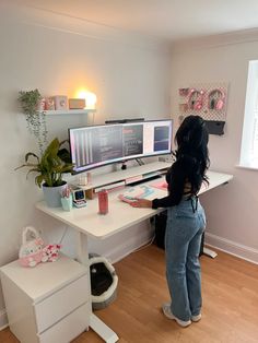 a woman standing in front of a computer desk