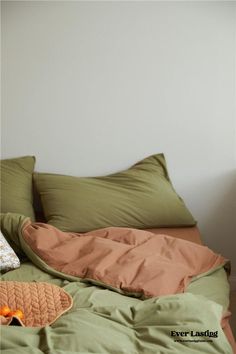 an unmade bed with green sheets and pillows