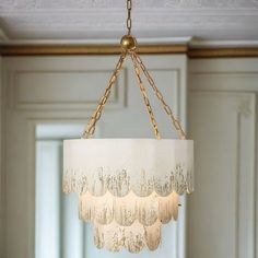 a chandelier hanging from the ceiling in a room with white walls and gold trim