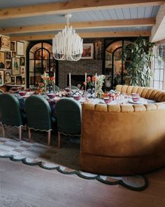 a large round table with green chairs around it in a dining room next to a fireplace