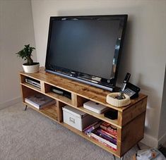 a flat screen tv sitting on top of a wooden entertainment center next to a plant