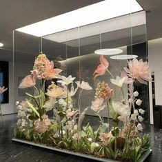 an arrangement of flowers is displayed in a glass case