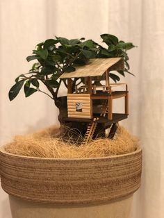 a small tree house sitting on top of a potted plant