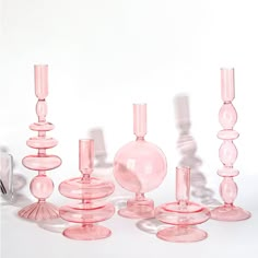 a group of pink glass vases sitting next to each other on a white surface