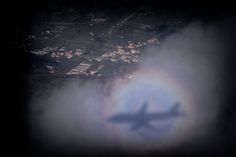 an airplane is flying in the sky with a halo around it that looks like a rainbow