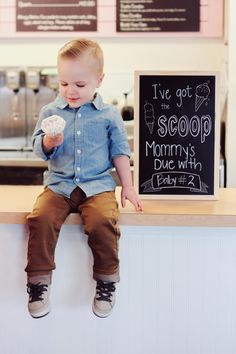 a young boy sitting on top of a counter holding a donut in his hand