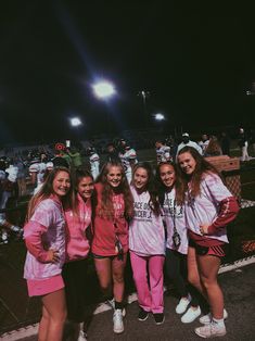 a group of young women standing next to each other on a tennis court at night