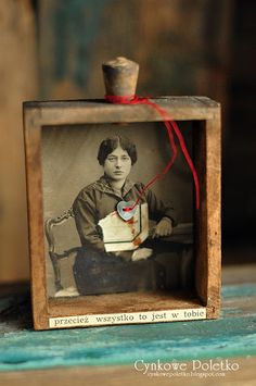 an old fashioned photo in a wooden frame with a red string attached to the top