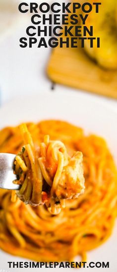 a fork full of spaghetti on top of a white plate with the words crockpot cheesy chicken spaghetti