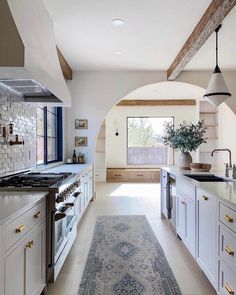 a kitchen with an archway leading into the living room and dining area, as well as a large rug on the floor