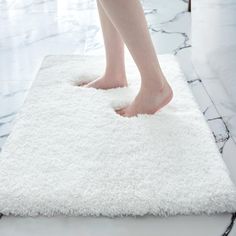 a person standing on top of a white rug with their feet in the bathroom floor