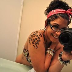 a woman taking a selfie with a camera in her hand and wearing a leopard print headband