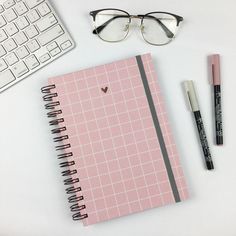 a pink notebook with glasses, pen and eyeglasses next to it