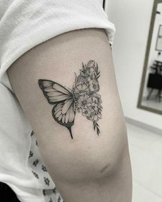 a butterfly and flowers tattoo on the right side of the thigh, it is black and white