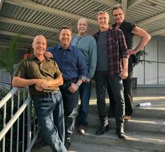 five men are standing on the steps in front of a building and posing for a photo