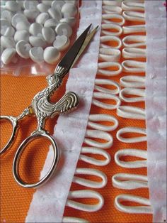 a pair of scissors sitting on top of a table next to white and orange material