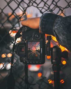 a person holding up a camera to take a photo with the city lights in the background