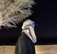 a person standing in front of a tree with snow on it and the sky behind them