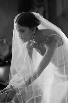 black and white photograph of a woman in wedding dress with veil over her head looking down