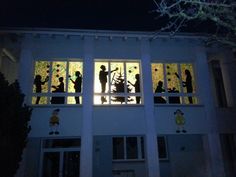 silhouettes of people are seen through the windows of a building at night time,