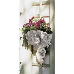 a white wall mounted planter with pink flowers in it's mouth and face