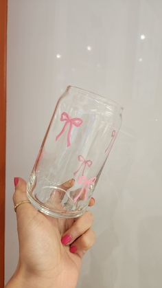 a hand holding a glass with pink bows on it