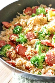 a skillet with rice, sausage and broccoli in it on a table